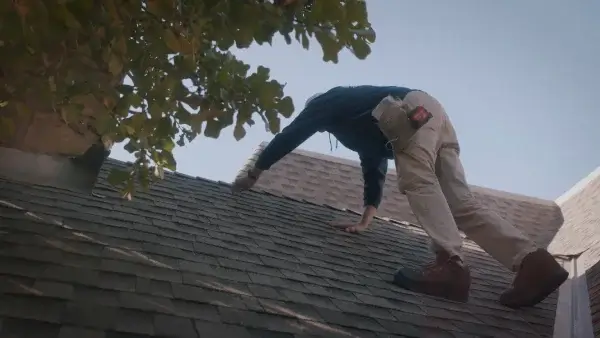 Roof inspection technician from Yates Roofing & Construction in OKC checking shingles on residential roof